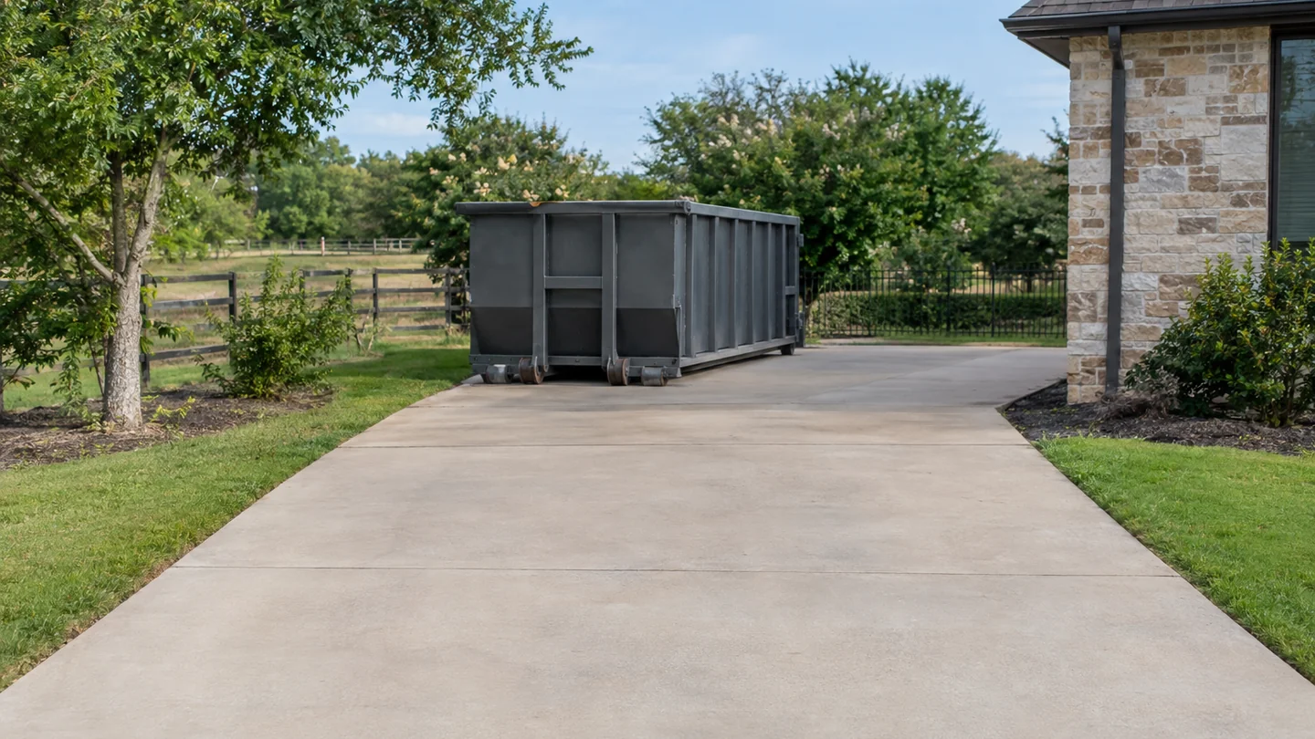 Empty unbranded roll-off beside a wide clear driveway with an unobstructed entrance.